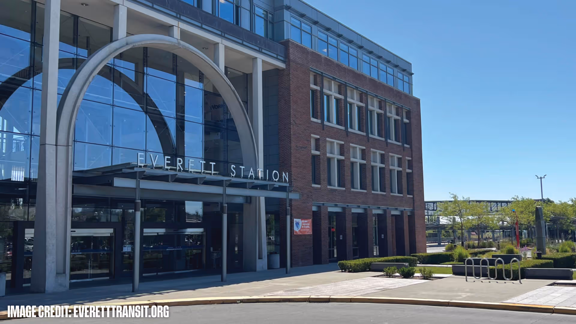 Front of Everett Station building with large glass windows, an arch entrance, and clear blue sky.
