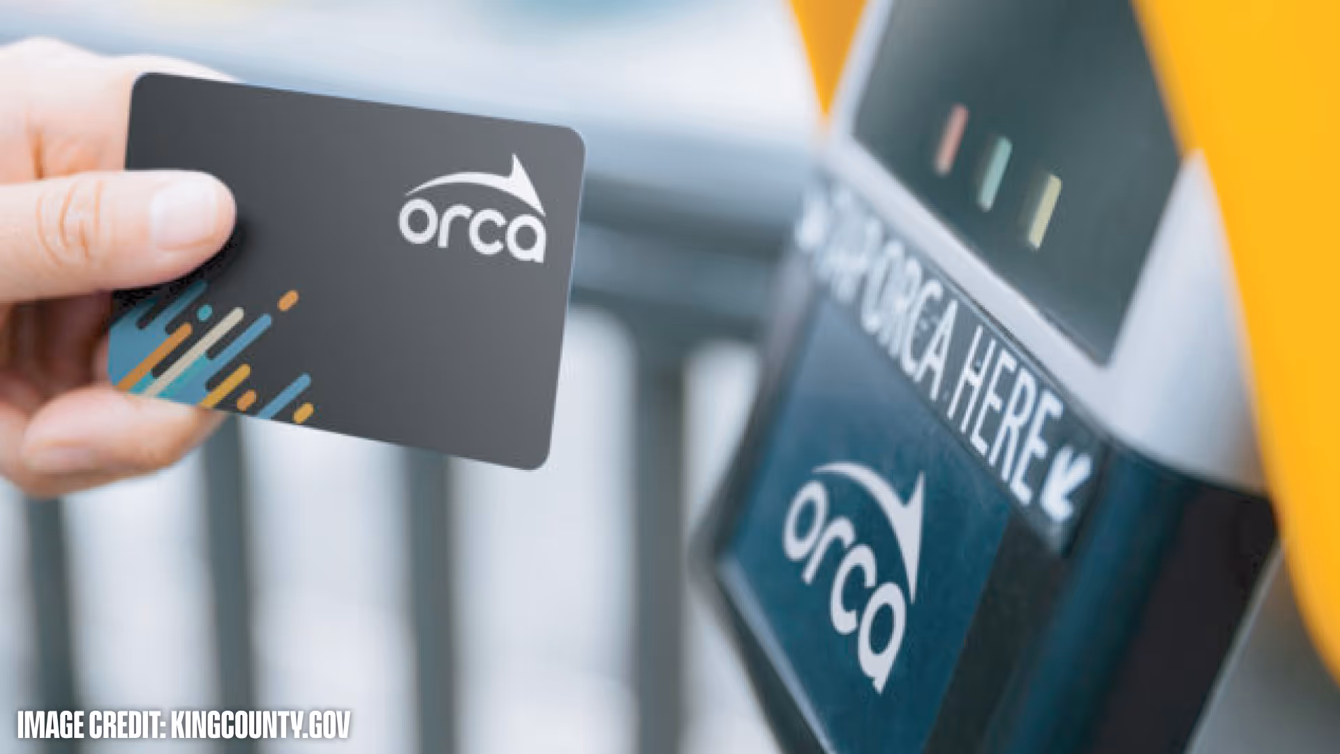 Hand holding an ORCA transit card near an ORCA card reader with a sign that says 'Tap ORCA here'.