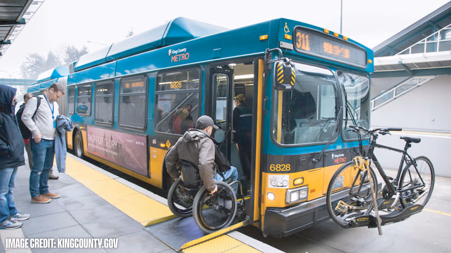 A person in a wheelchair boarding a King County Metro bus equipped with a bike rack holding two bicycles.