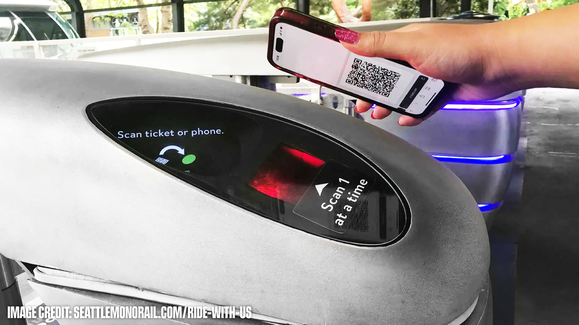 Hand holding a phone displaying a QR code to scan on a ticket validator with instructions to scan ticket or phone.