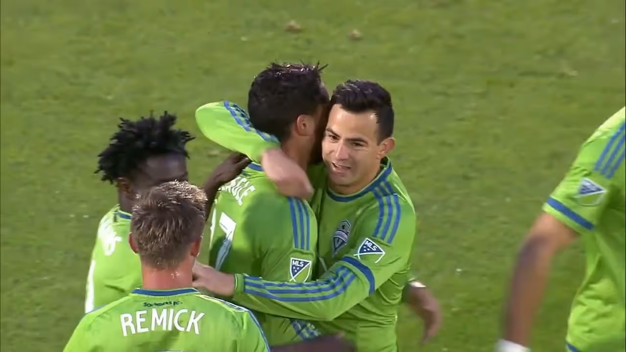 Seattle Sounders soccer players in green celebrating a goal on the field.