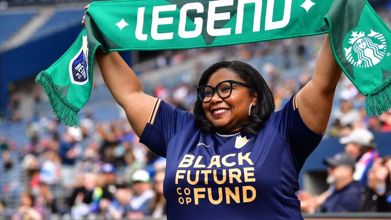 Smiling woman holding green scarf with Legend text at a crowded stadium event.