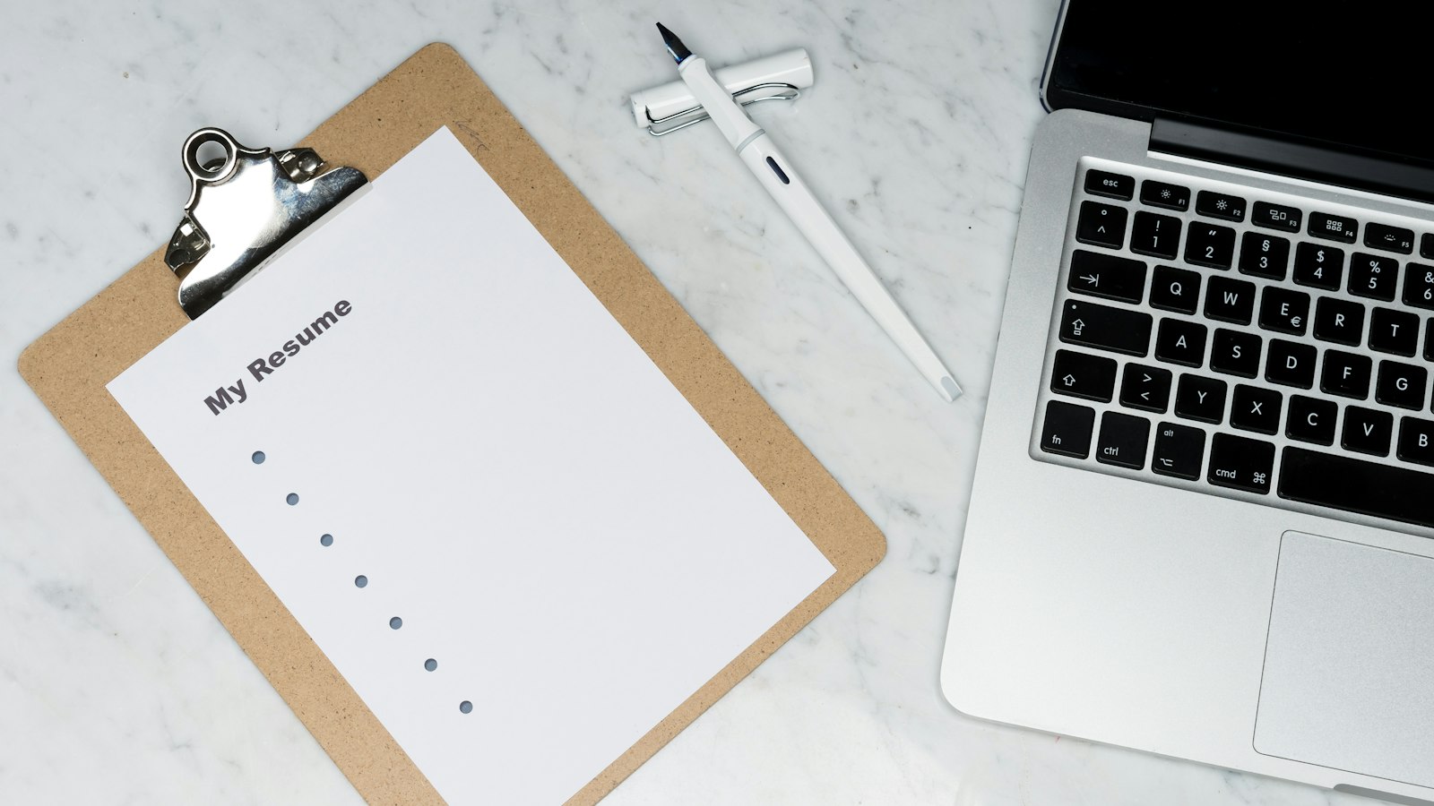 A printed one-page resume next to a laptop on a desk