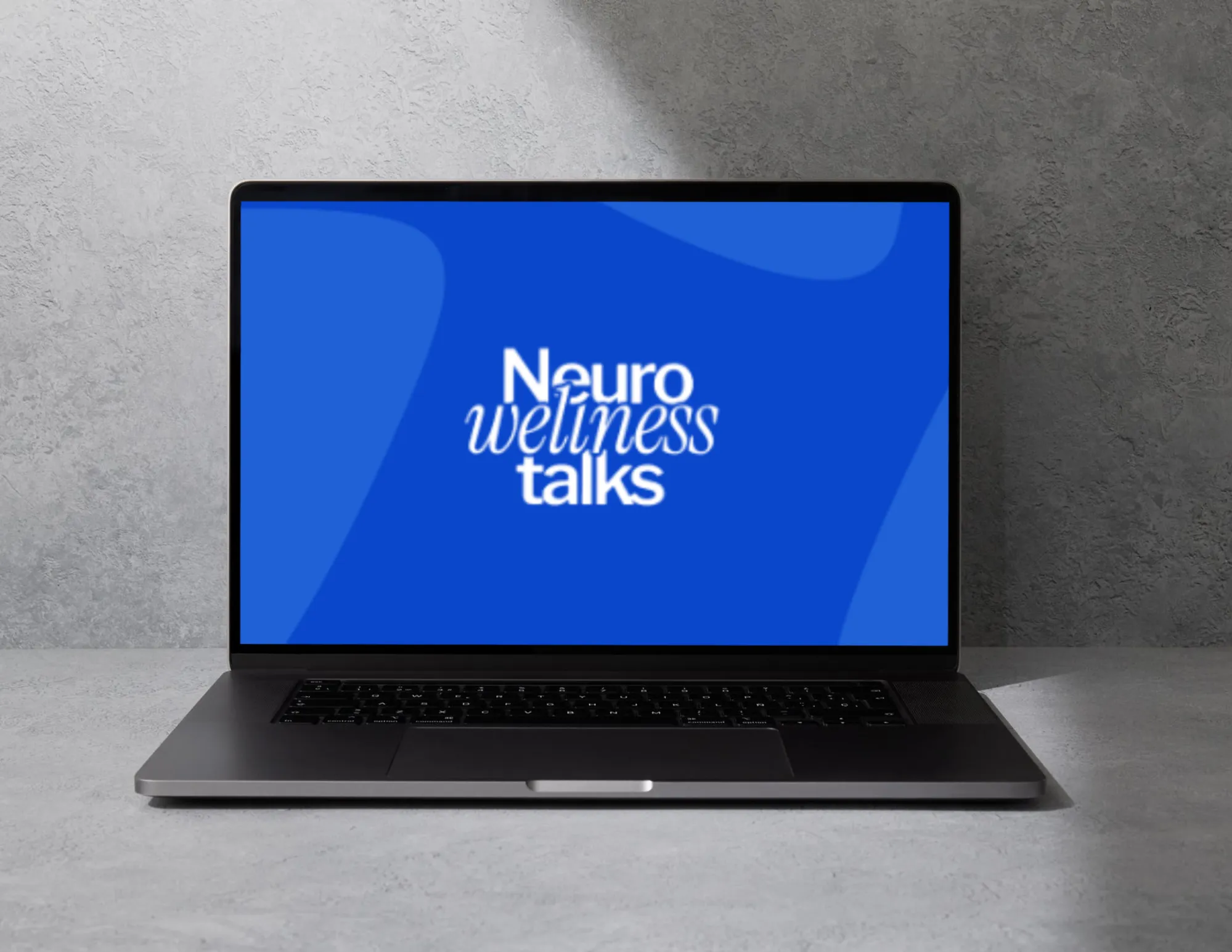 Laptop on gray surface showing a blue screen with the text Neuro wellness talks.