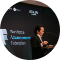 A man speaking at a podium with a screen behind him displaying the text Workforce Advancement Federation.