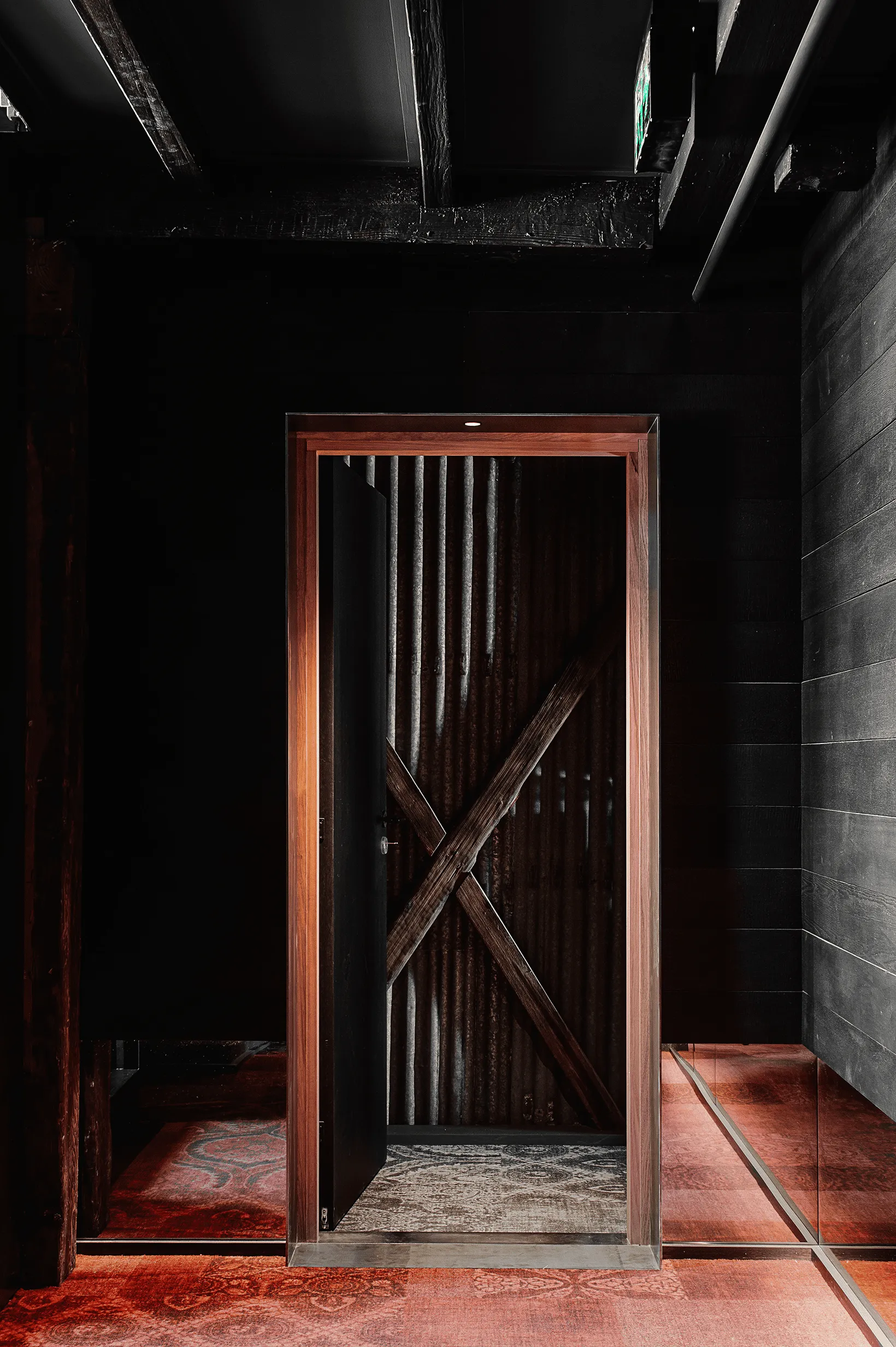 An inviting doorway featuring wooden details and a red patterned carpet.