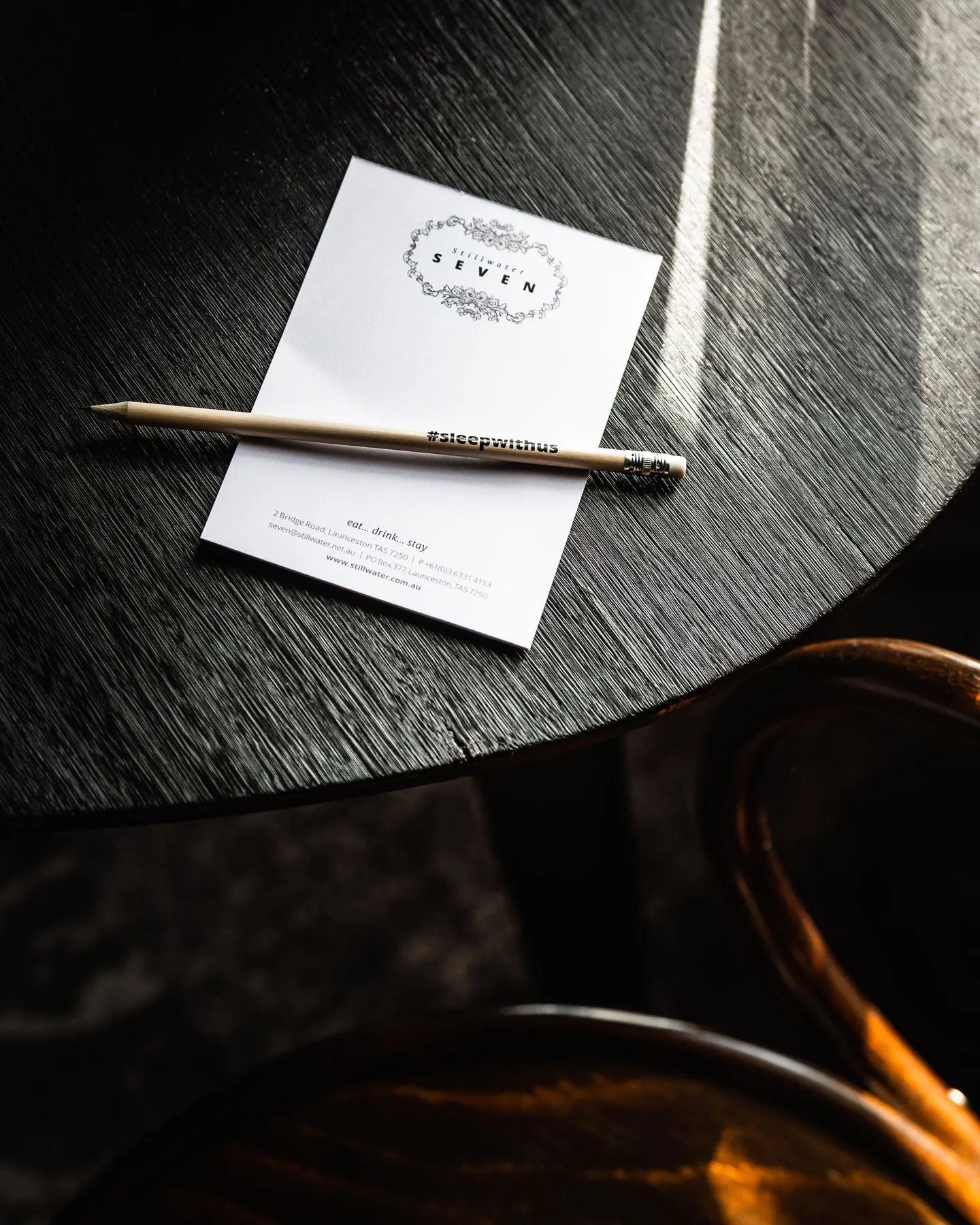 a black wooden table and chair, with a stillwater notepad and pencil