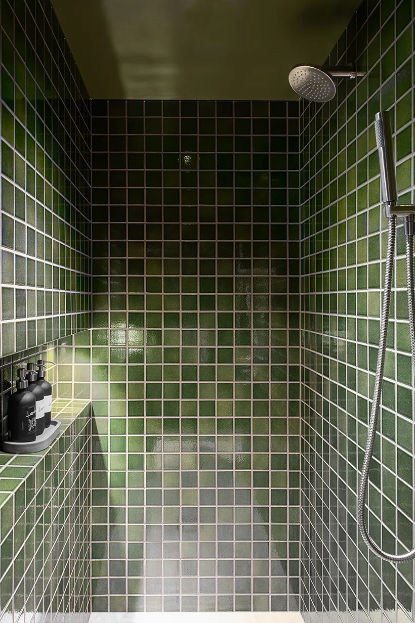 A well designed batrhoom featuring beautiful green ceramic tiles and amenities.