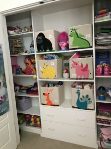A kid's closet organized with storage bins.