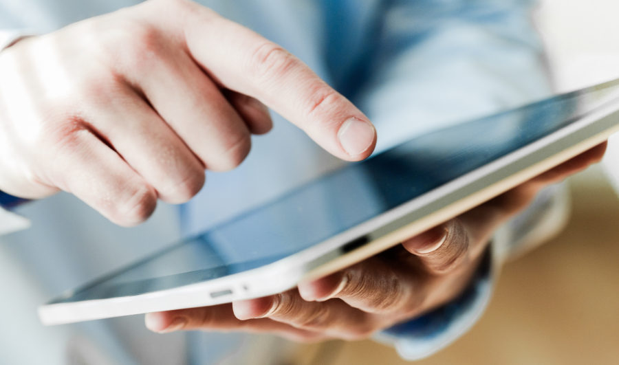 A man wearing glasses and a grey hoodie is focused on his work at a computer.