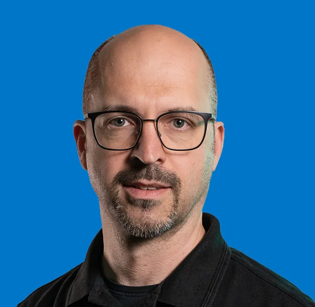 Portrait of Wolfgang Bodensteiner, on solid blue background.