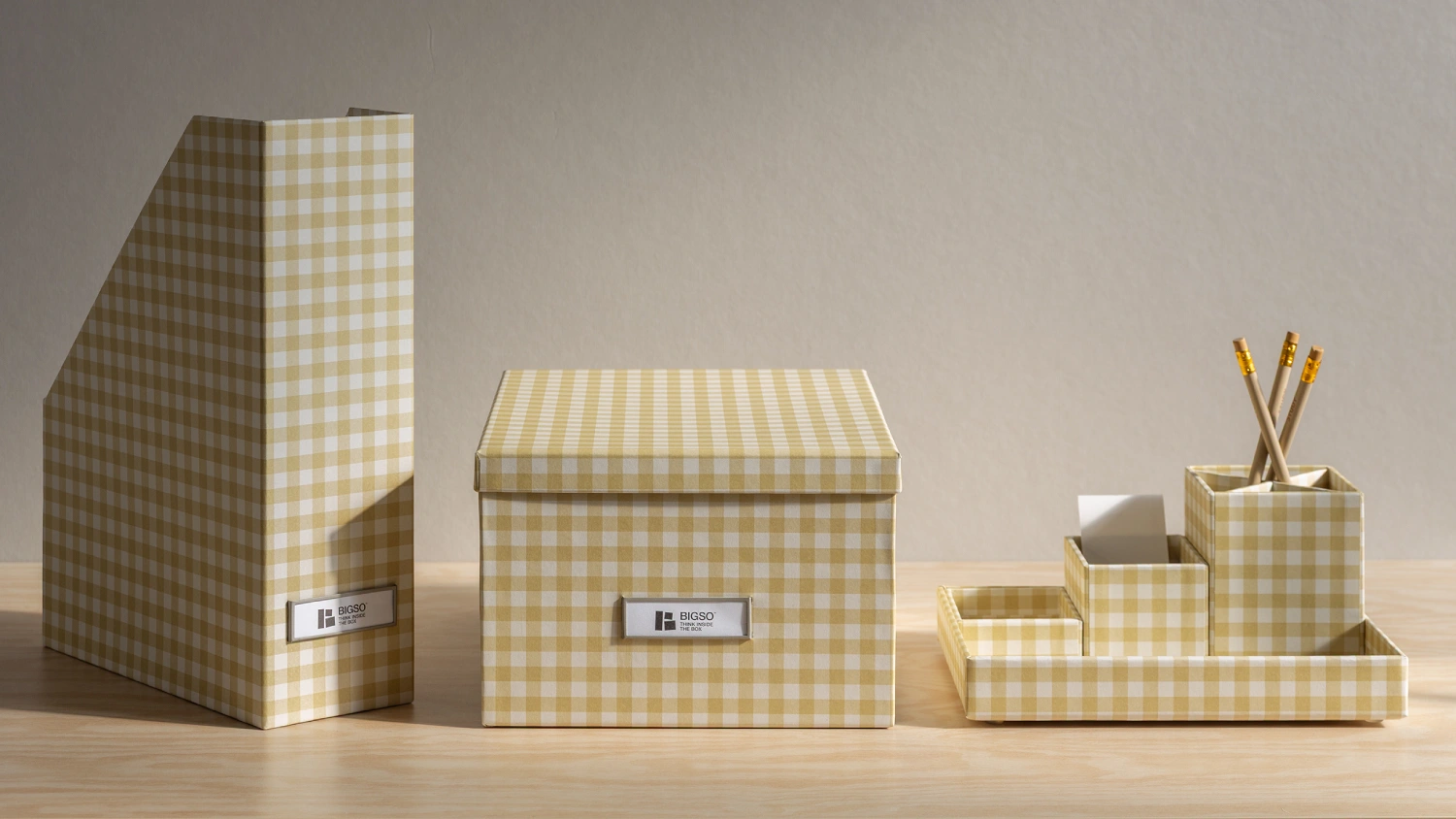 Bigso yellow checkered storage collection, including a magazine file holder, lidded storage box, and desk organizer with compartments for pencils and notes. Elegant Scandinavian design crafted from recycled fiberboard and paper, combining style and functionality for sustainable home and office organization.