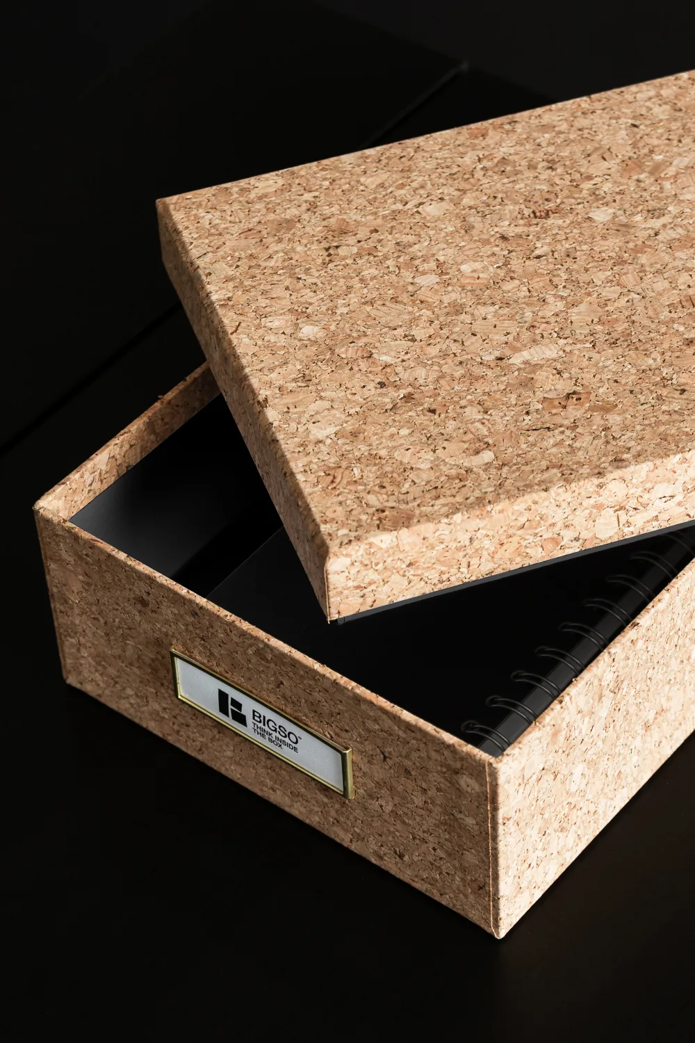 Bigso cork storage box with open lid, showing neatly stored spiral notebooks inside. Eco-friendly Scandinavian storage solution made from natural cork and recycled materials, ideal for sustainable home and office organization.