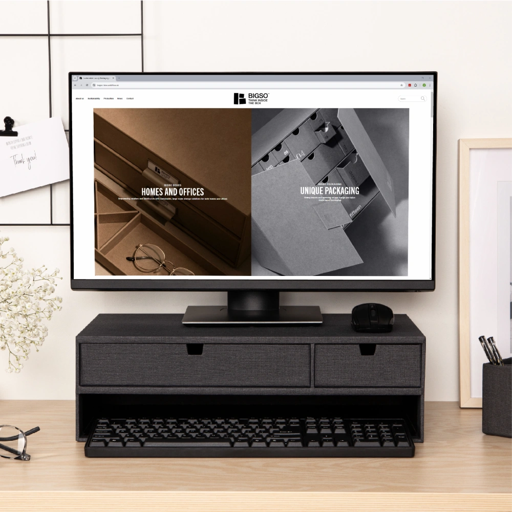 Modern home office setup with a computer screen showing Bigso’s new website, placed on a black fabric desktop drawer organizer with keyboard and mouse for stylish workspace storage.
