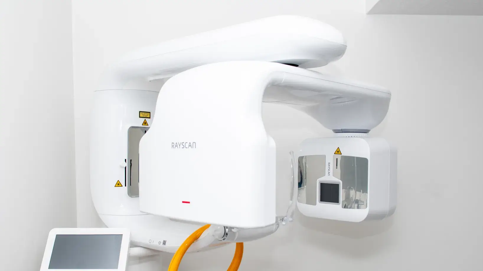White Rayscan dental panoramic X-ray machine with a touchscreen control panel in a clinical setting.