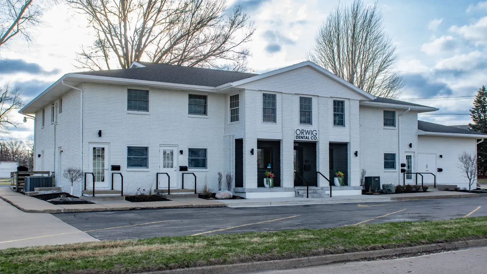 White two-story building with Orwig Dental Co. sign above the main entrance and surrounding bare trees.
