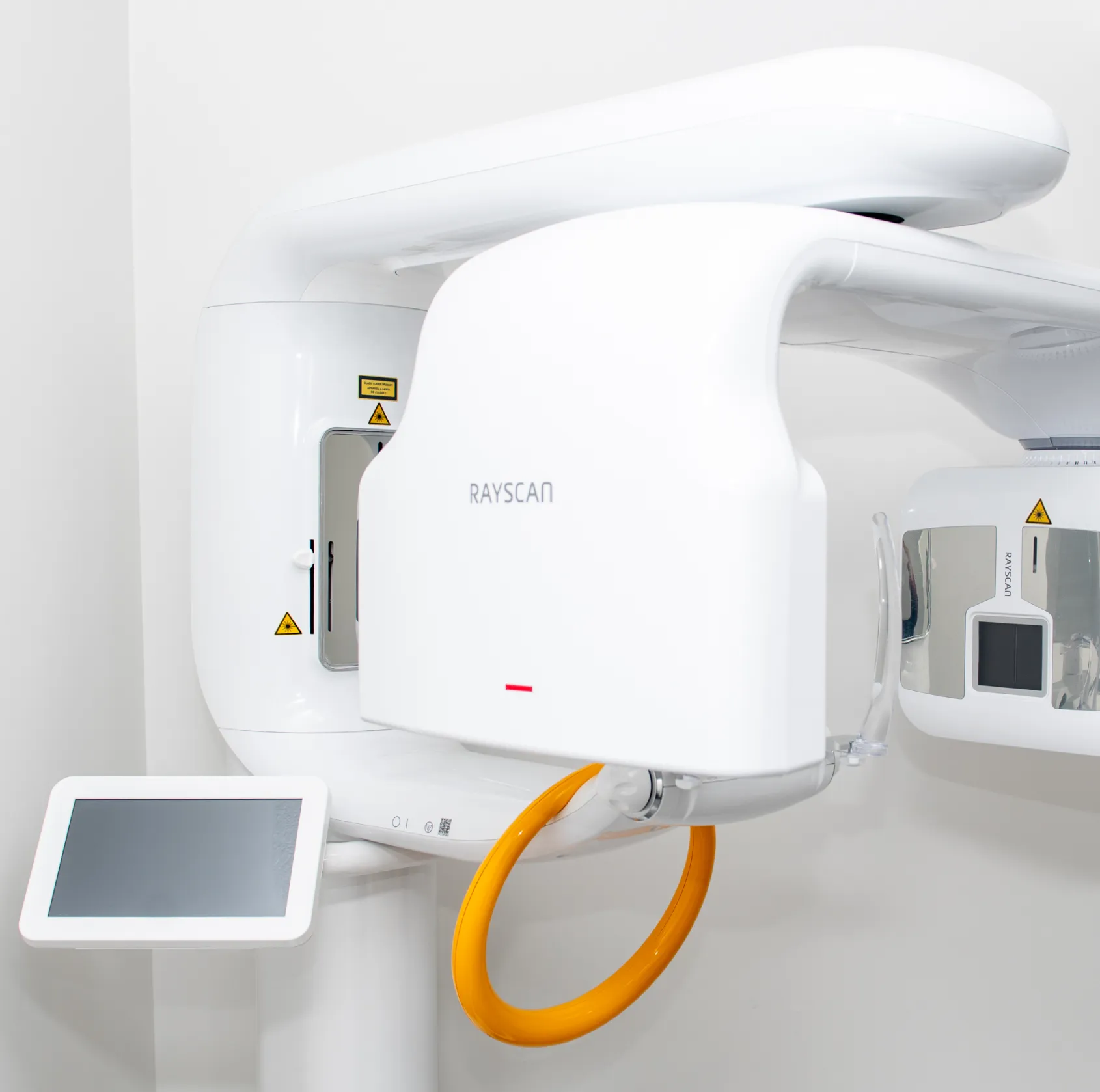 White Rayscan dental imaging machine with a yellow circular handle and a touchscreen display.