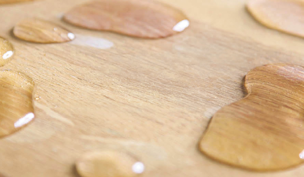Water droplets resting on a wood surface.