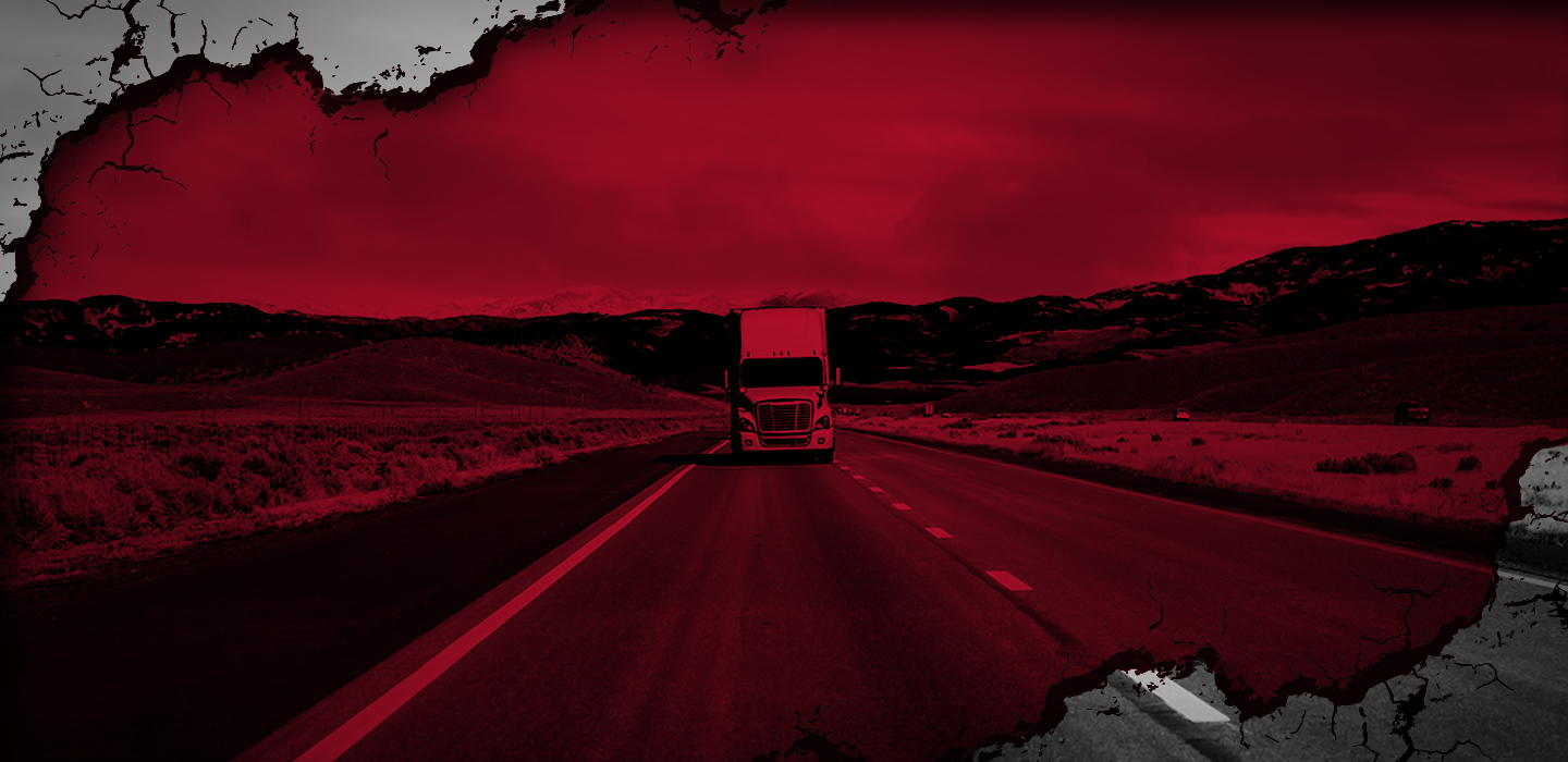 A freight truck traveling along a rural highway, framed by cracked flooring.