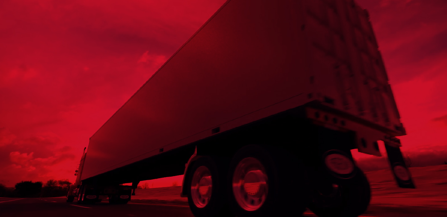 A dry van trailer viewed from below against a red sky.