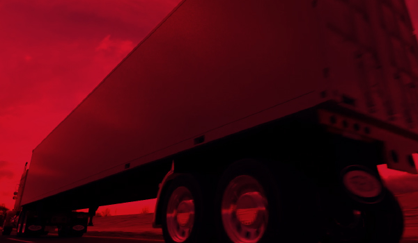 A dry van trailer viewed from below against a red sky.