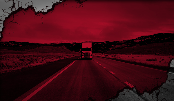 A freight truck traveling along a rural highway, framed by cracked flooring.