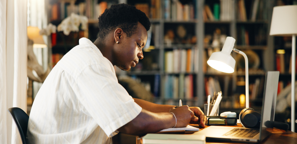 Student sitting at desk with his laptop and studying