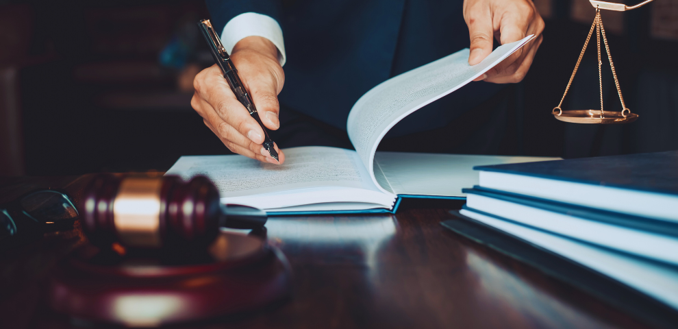 Man writing in a large book next to a gavel
