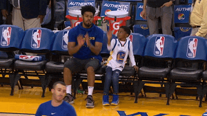GIF of person sitting on the sidelines at a basketball game demonstrating proper form for shooting a basketball to a little kid
