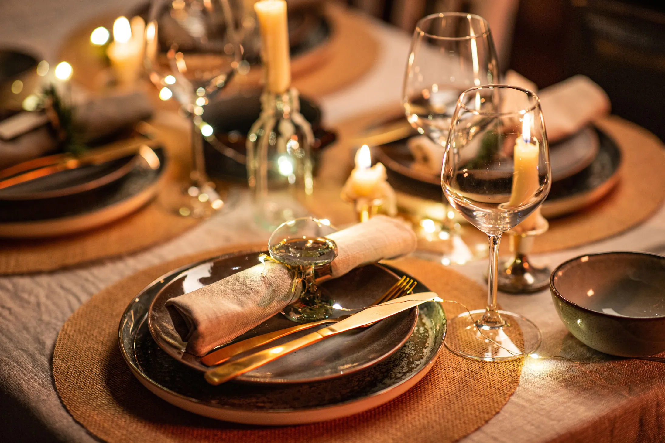 A candlelit table with plates, cutlery, and napkins