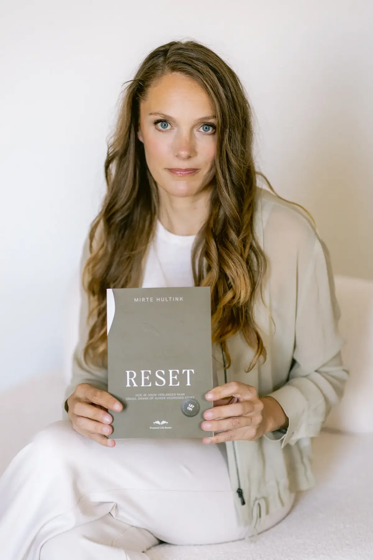 Mirte Hultink met het RESET-boek over het stoppen van verlangen naar drugs, drank of suiker.
