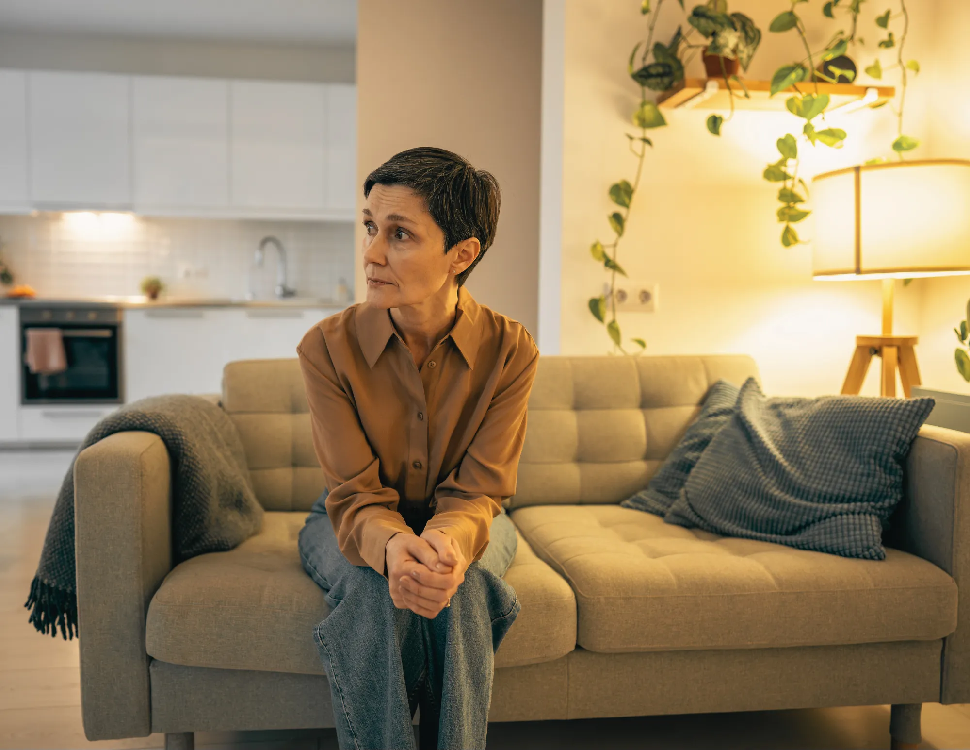 Vrouw zit alleen op de bank en voelt zich onrustig zonder alcohol of drugs.