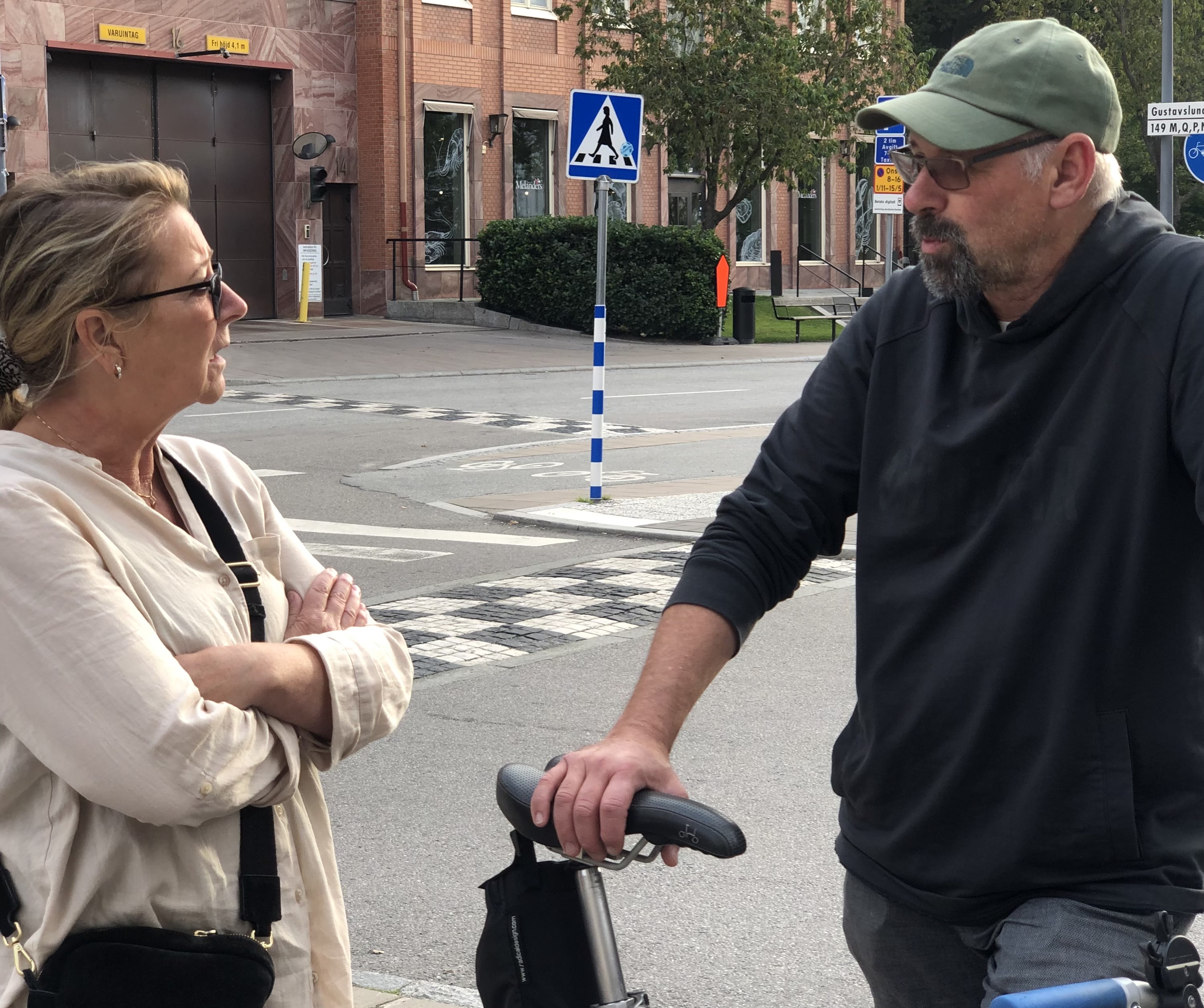 Ann och Stefan i samspråk på en gata. Stefan håller i en cykel.