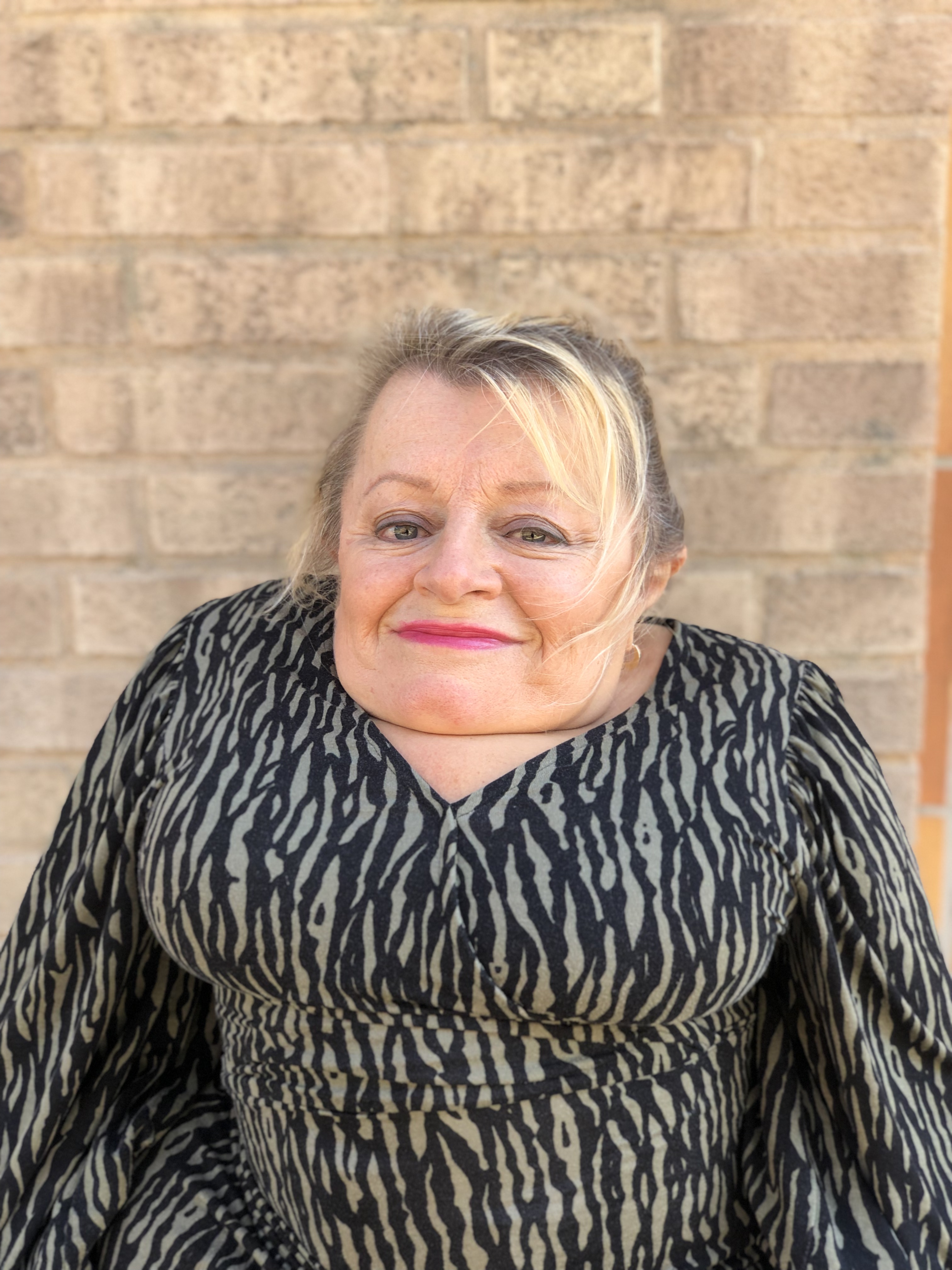 En bild på Susanne framför en tegelvägg