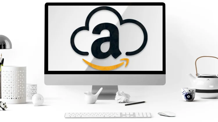 White desk with a tea pot and pencil and an apple computer with an amazon cloud logo
