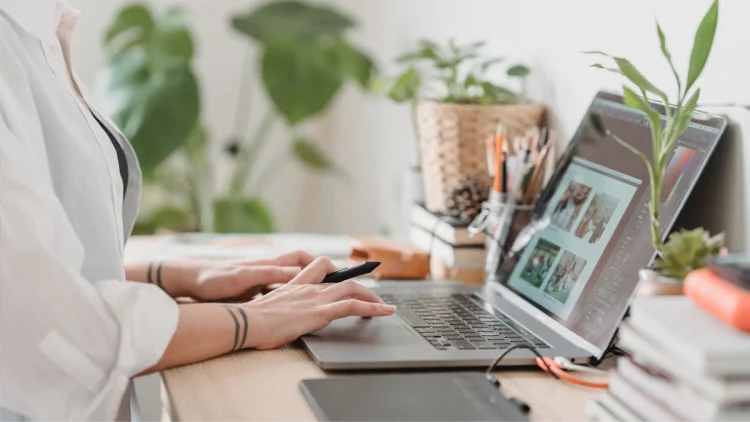 Person in a white collared shirt types on laptop computer