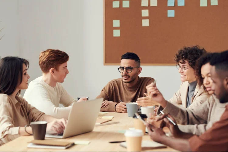 Several people discussing ideas and brainstorming while sitting on a table