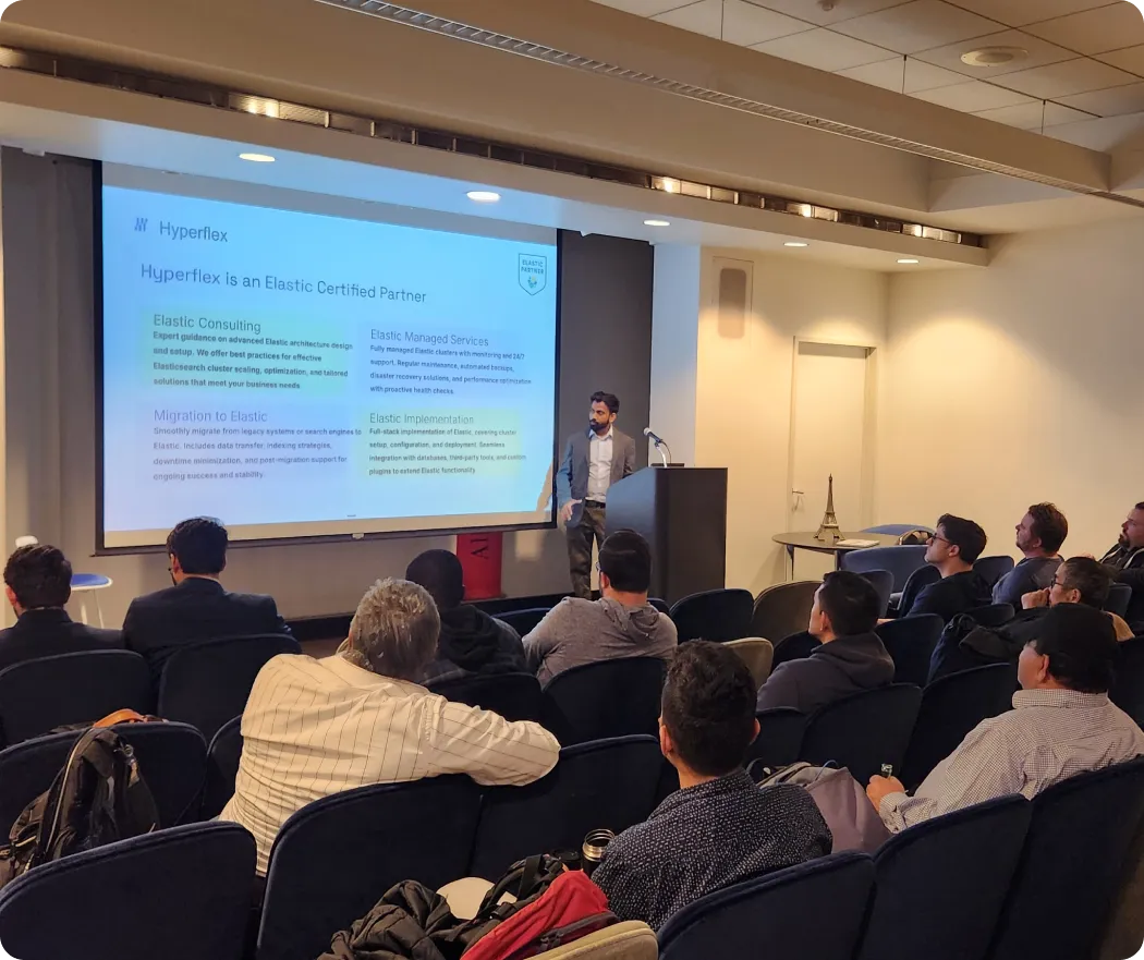 Man in suit giving presentation about Hyperflex as an Elastic Certified Partner to seated audience.