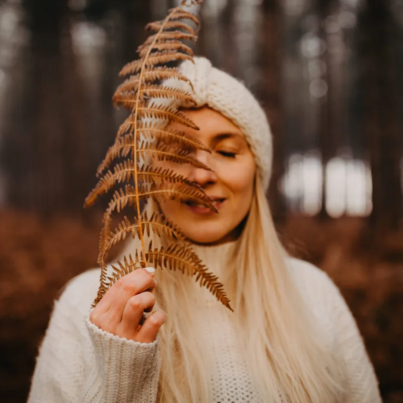 Shannen Rasking houdt een varen voor haar gezicht in het bos