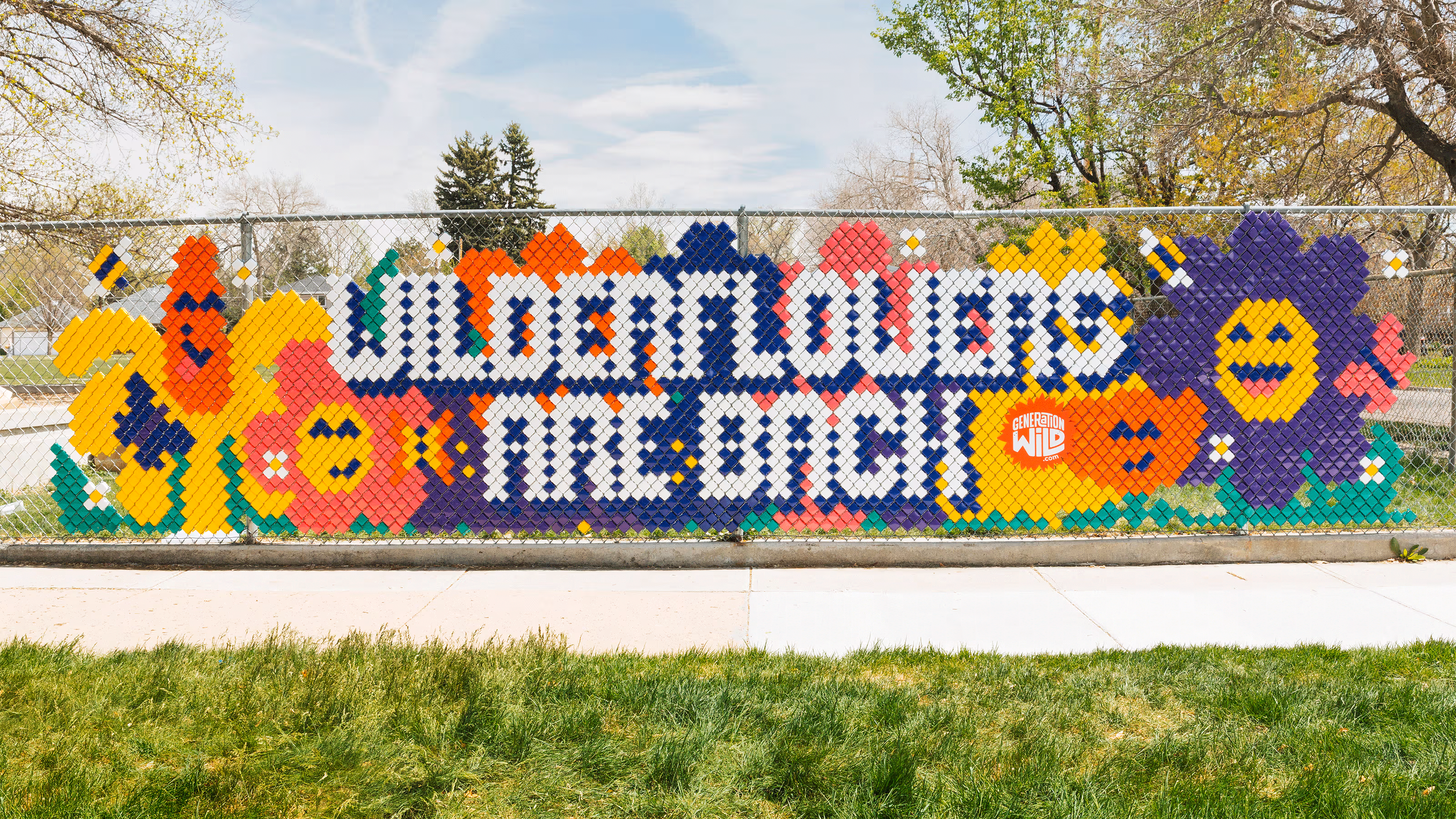 School fence with art that reads wilderflowers are back