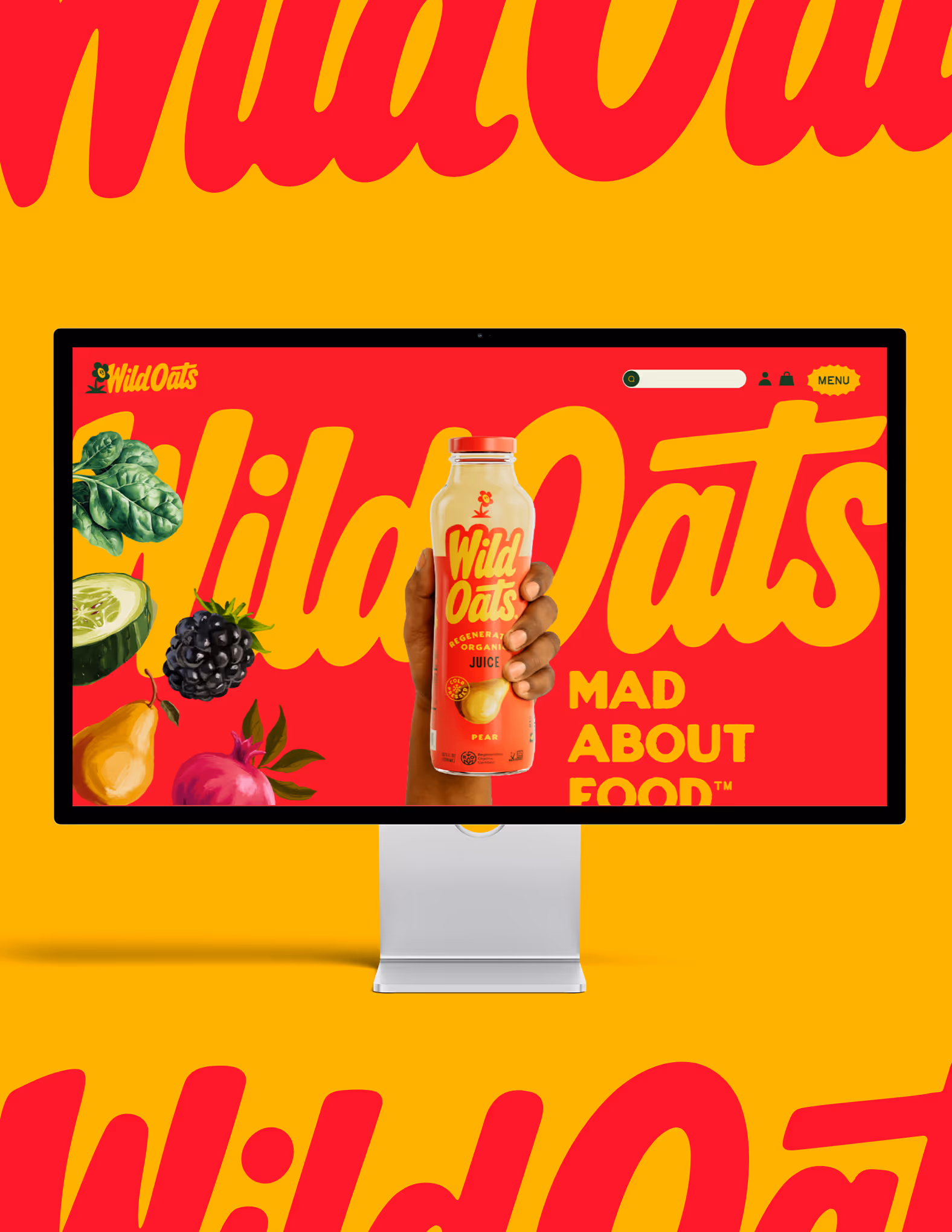 Hand holding a bottle of Wild Oats organic pear juice displayed on a computer screen / website with colorful fruits and bold Wild Oats branding on a red and yellow background.
