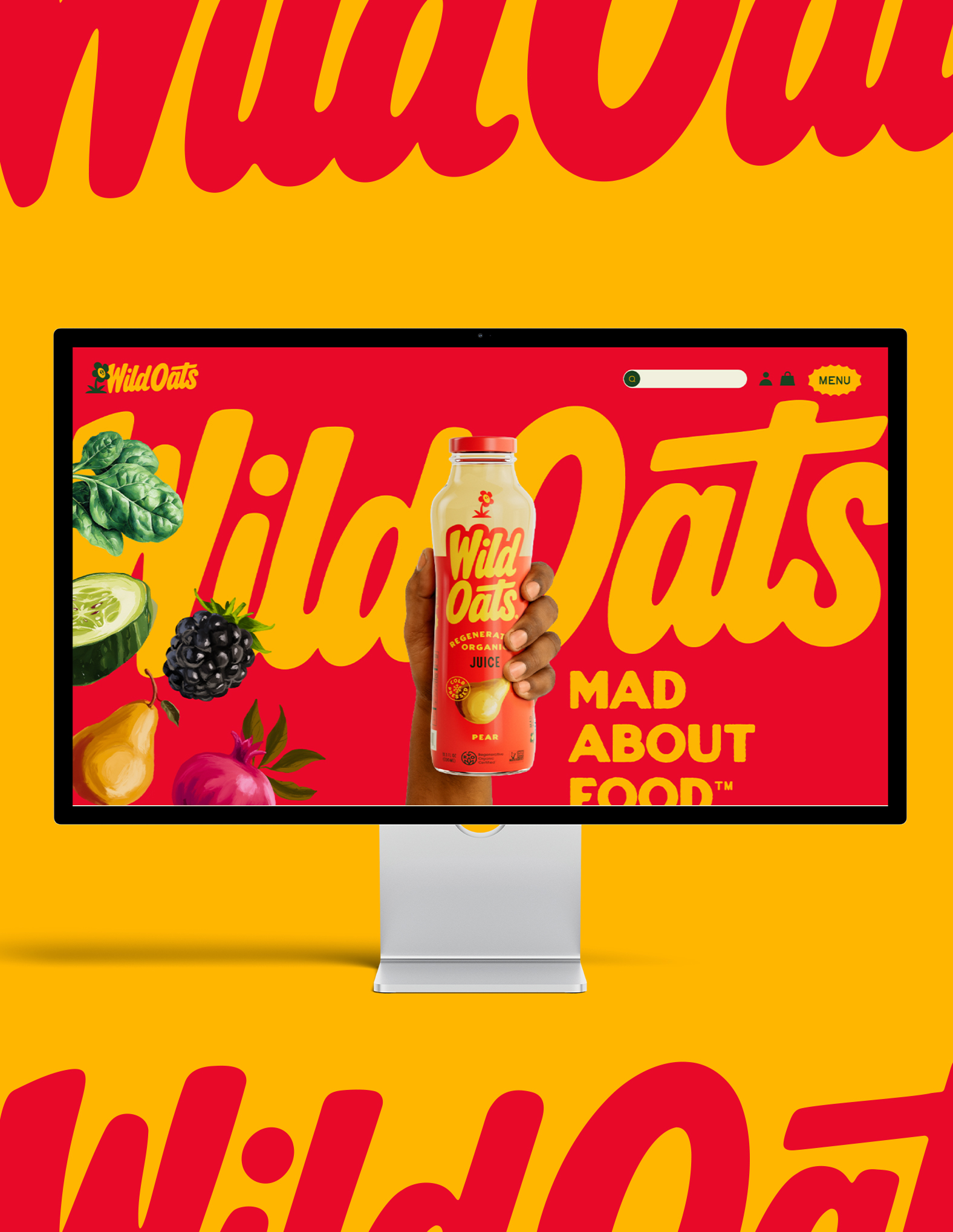 Hand holding a bottle of Wild Oats organic pear juice displayed on a computer screen / website with colorful fruits and bold Wild Oats branding on a red and yellow background.