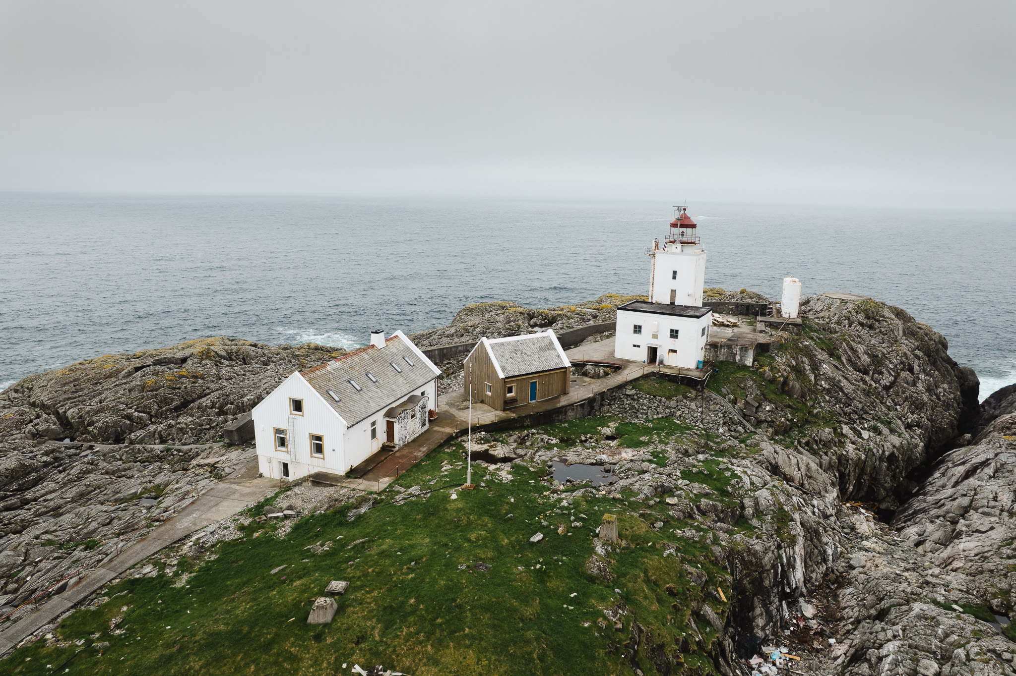 Luftfoto av Marstein Fyr med fyrtårn, bygninger og havet som omgir øya.