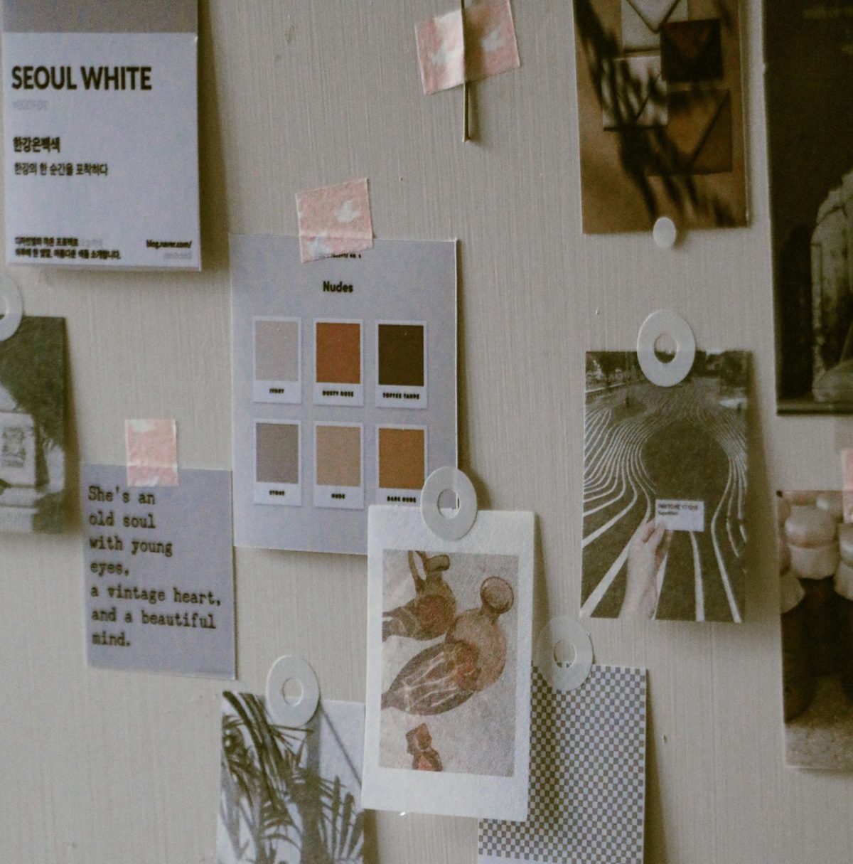 A pinned mood board of colour swatches, prints and photographs on a pale wall
