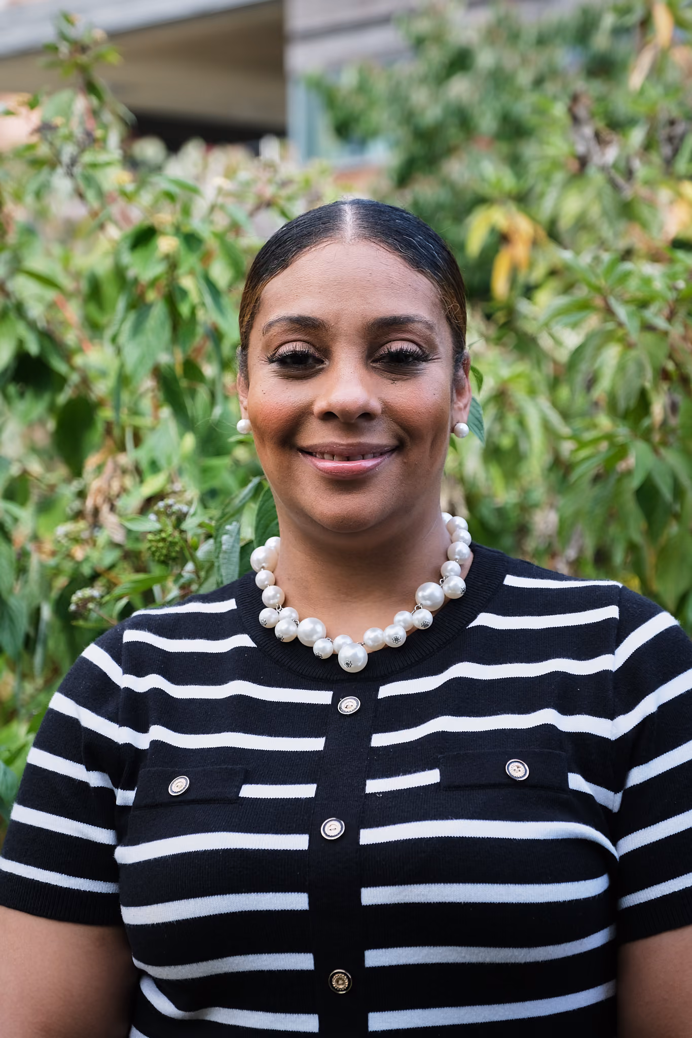 Staff portrait of Ashley Rougier smiling outdoors near greenery