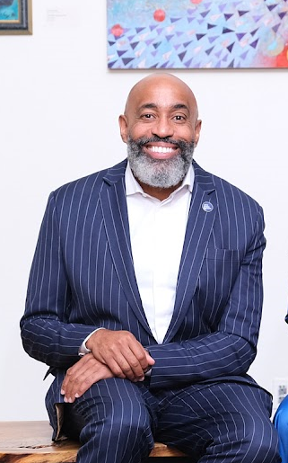 Dr. Khalek Kirkland smiling in a navy pinstripe suit