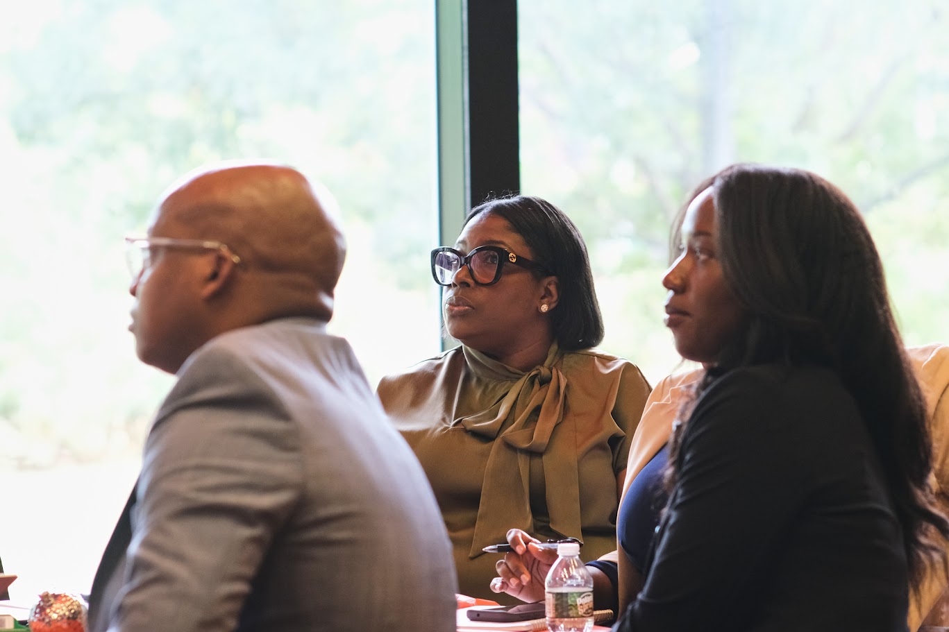 Three attendees listening attentively during a school district meeting