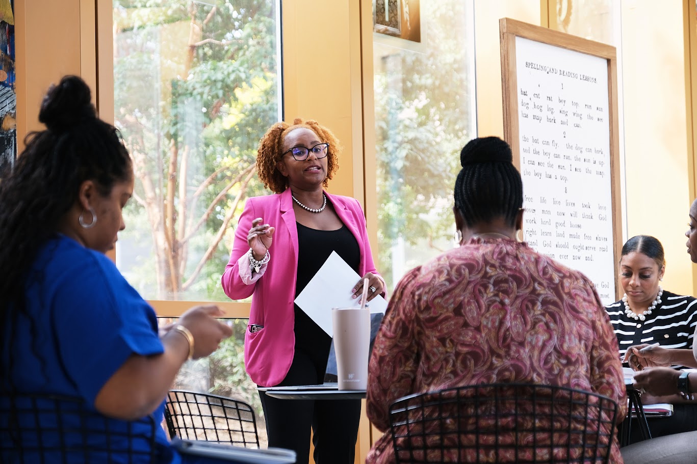 Educator in pink blazer presenting to a small group of adults