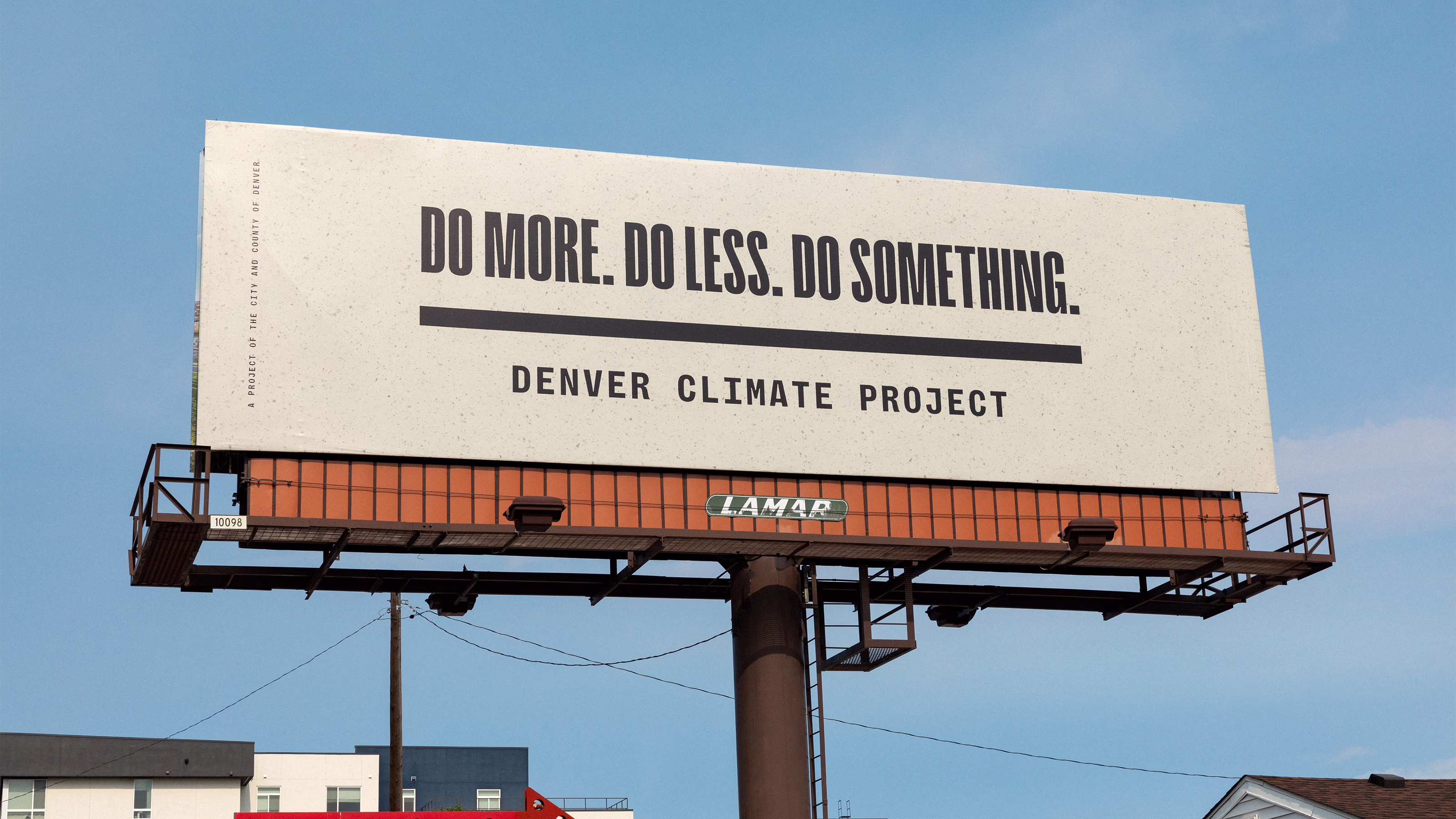 Photo of a tan billboard on a sunny day that reads "DO MORE. DO LESS. DO SOMETHING. Denver Climate Project" in black all caps type in front of a blue sky.