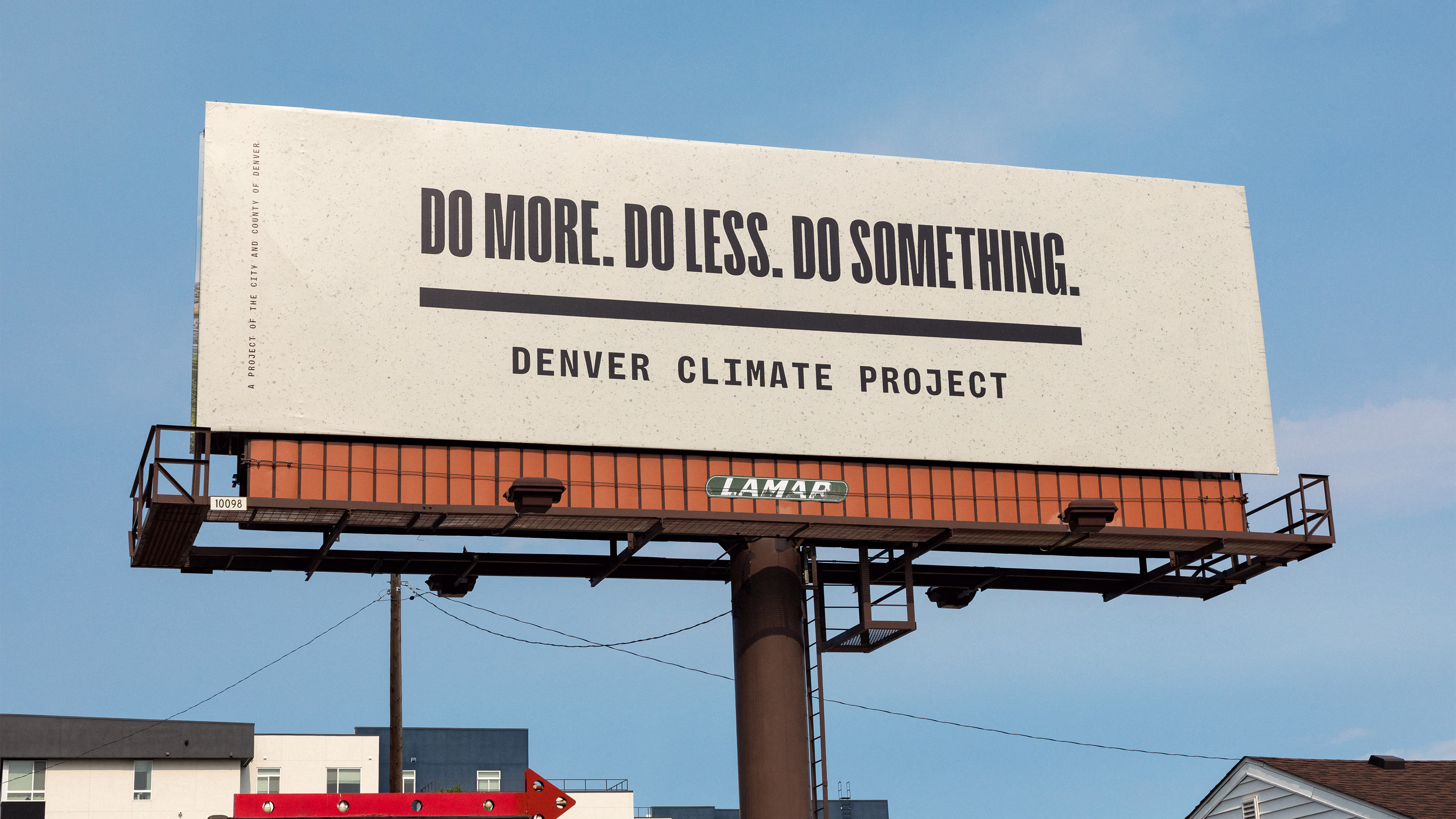 A tan billboard on a blue sky that reads "DO MORE. DO LESS. DO SOMETHING. DENVER CLIMATE PROJECT"